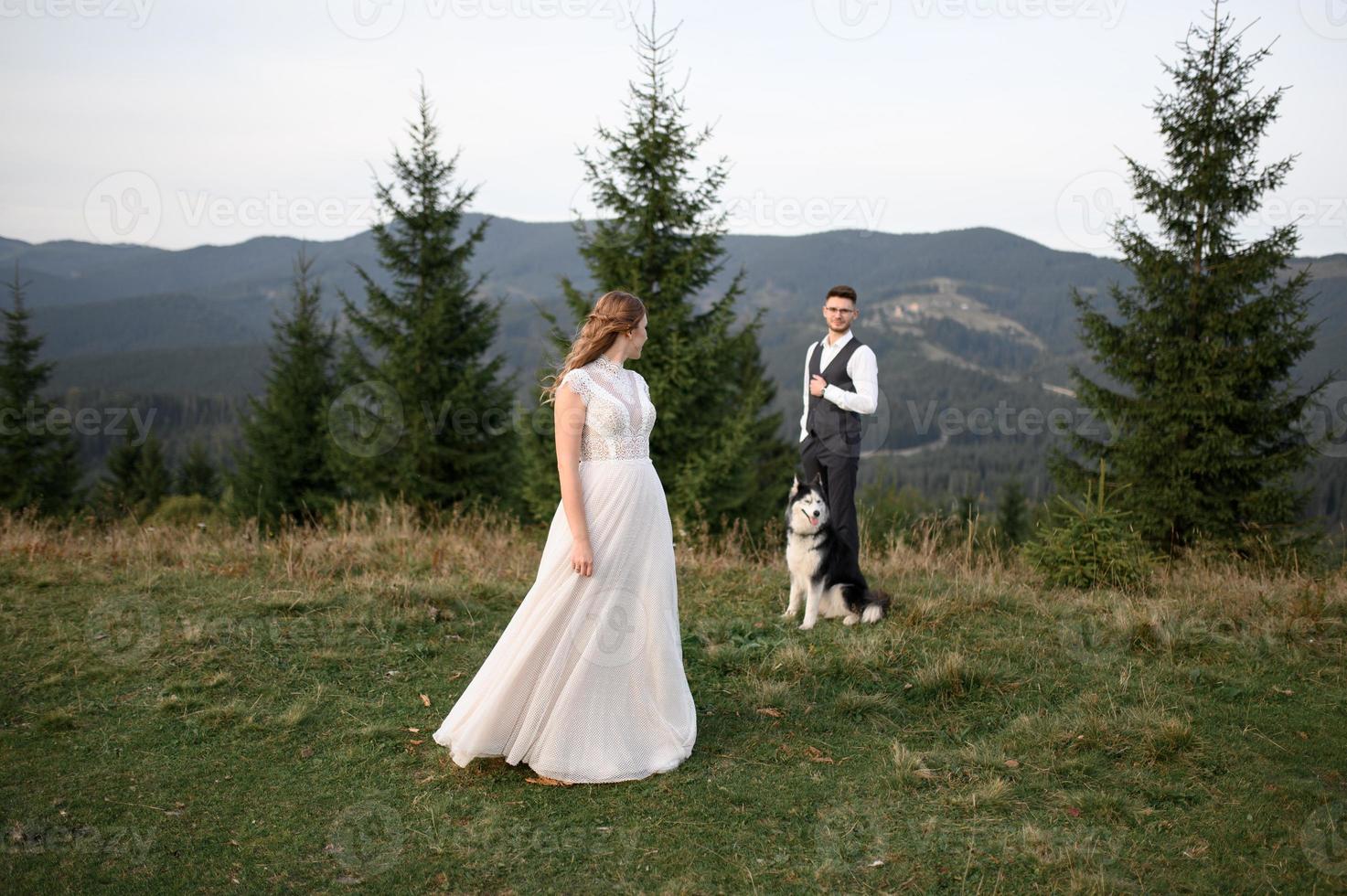 happy stylish bride and groom running and having fun in mountains on summer sunny day photo
