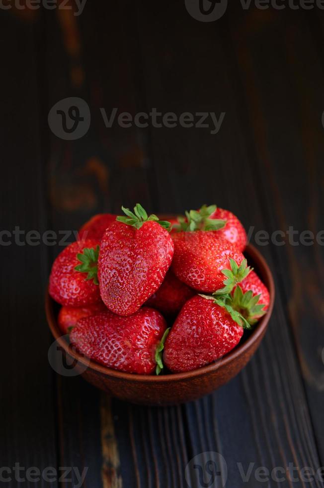 A bowl of red juicy strawberries on rustic wooden table. Healthy and diet snack food concept. photo