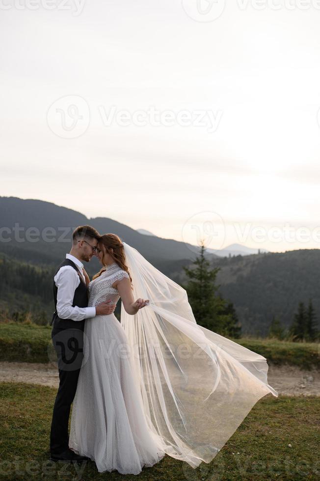 happy stylish bride and groom running and having fun in mountains on summer sunny day photo