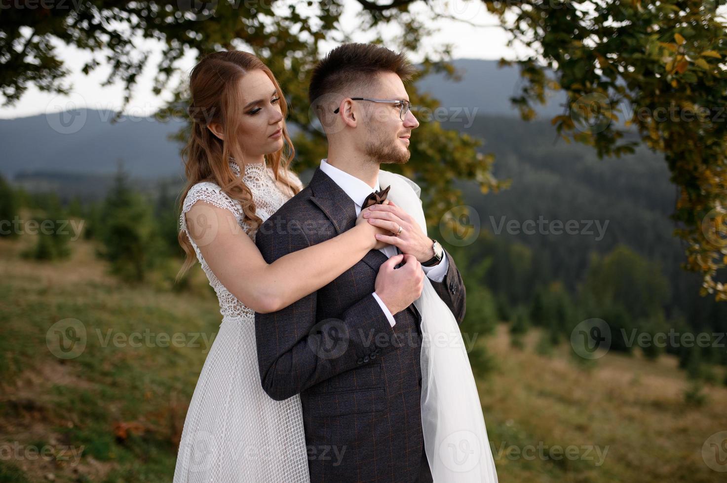happy stylish bride and groom running and having fun in mountains on summer sunny day photo