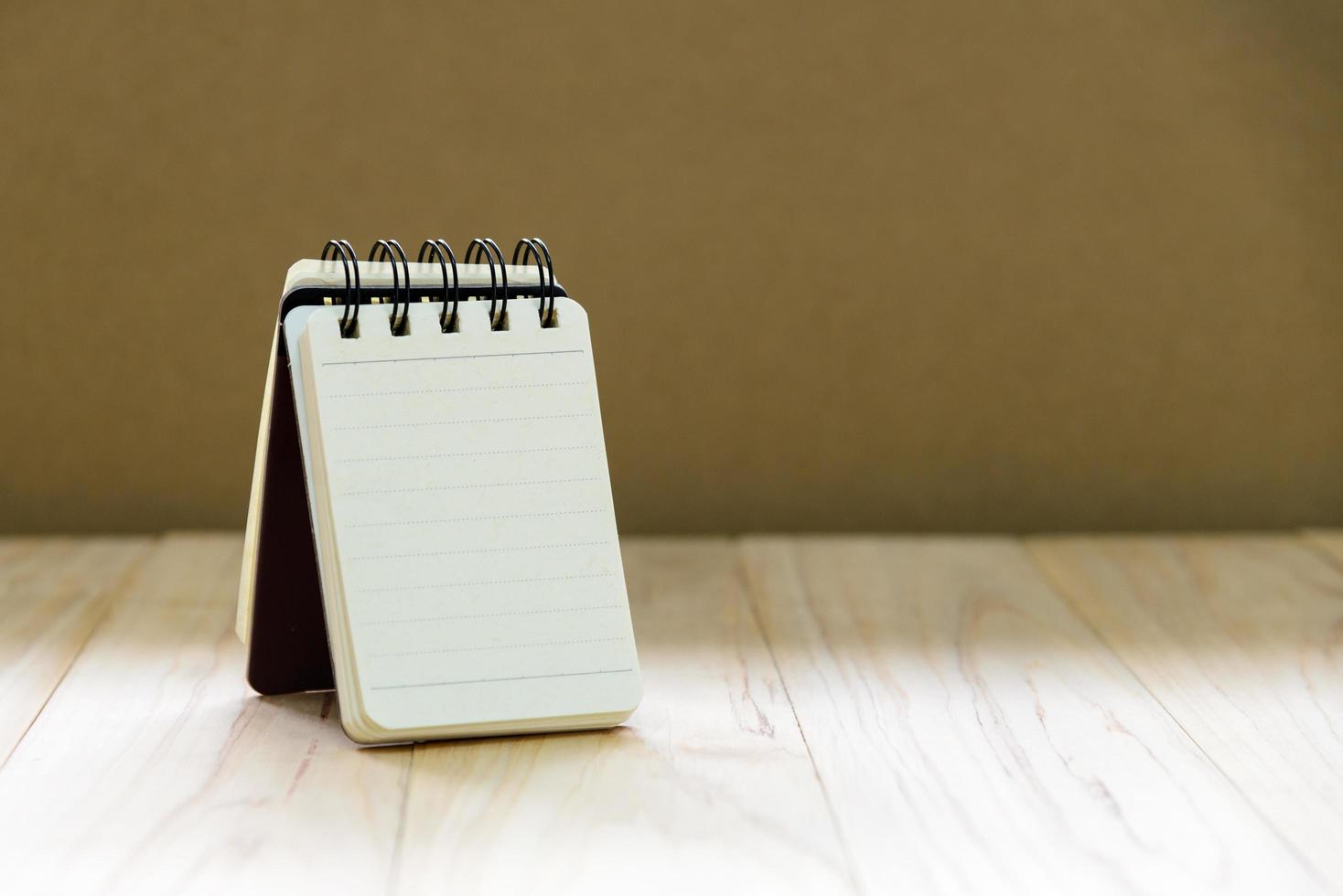 simulacros de papel de cuaderno pequeño o soporte de bloc de notas en una mesa de madera para escribir información con espacio de copia foto