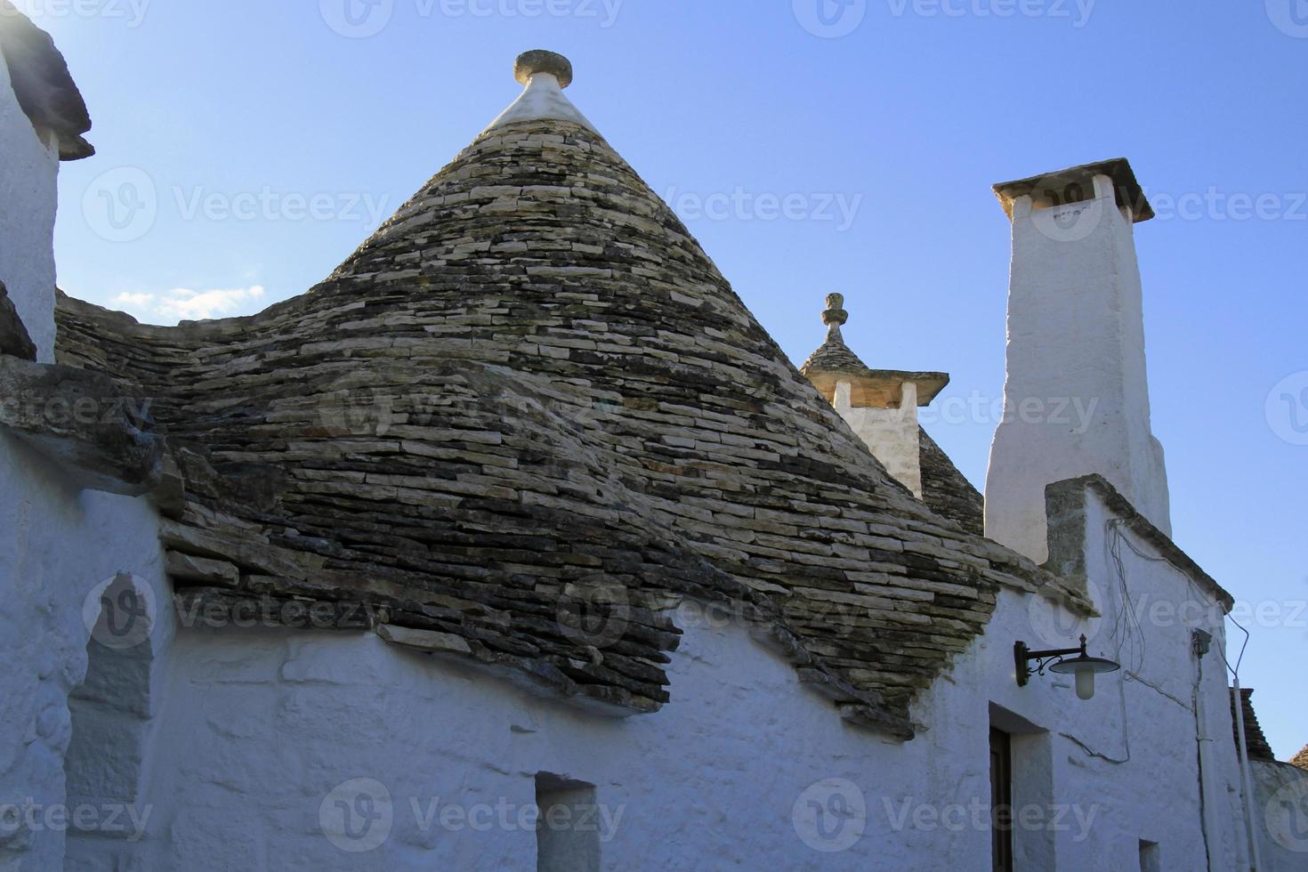 The characteristic Trulli in Alberobello, Italy, against a blue sky photo