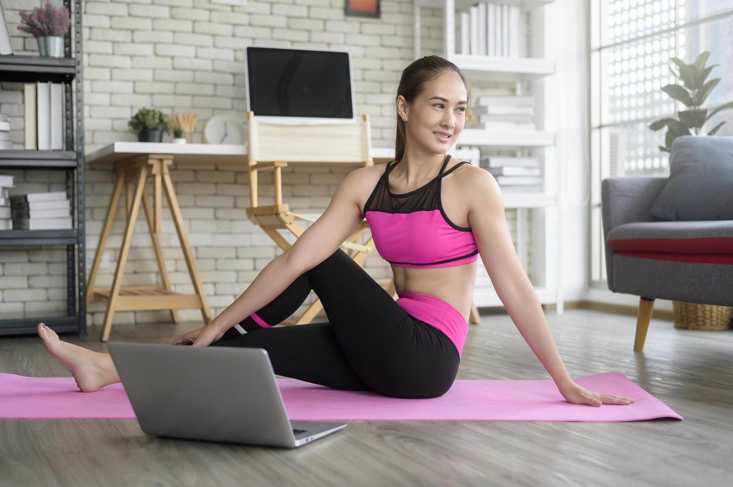 mujer joven en forma practicando yoga en casa a través de clases en línea con instructor profesional, deporte y concepto de estilo de vida saludable. foto