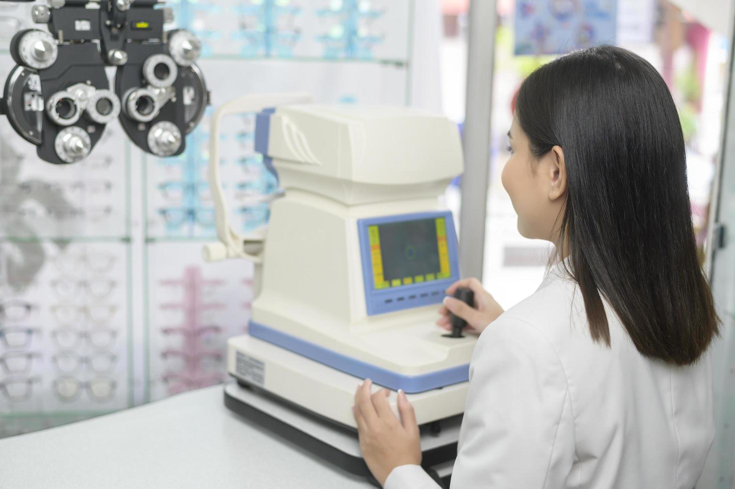 Young ophthalmologist doing a visual test for customer using autorefractor in optical center, eyecare concept. photo