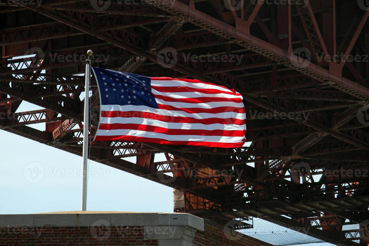 American flag waving in the wind next to the Golden Gate Bridge in San Francisco, California photo