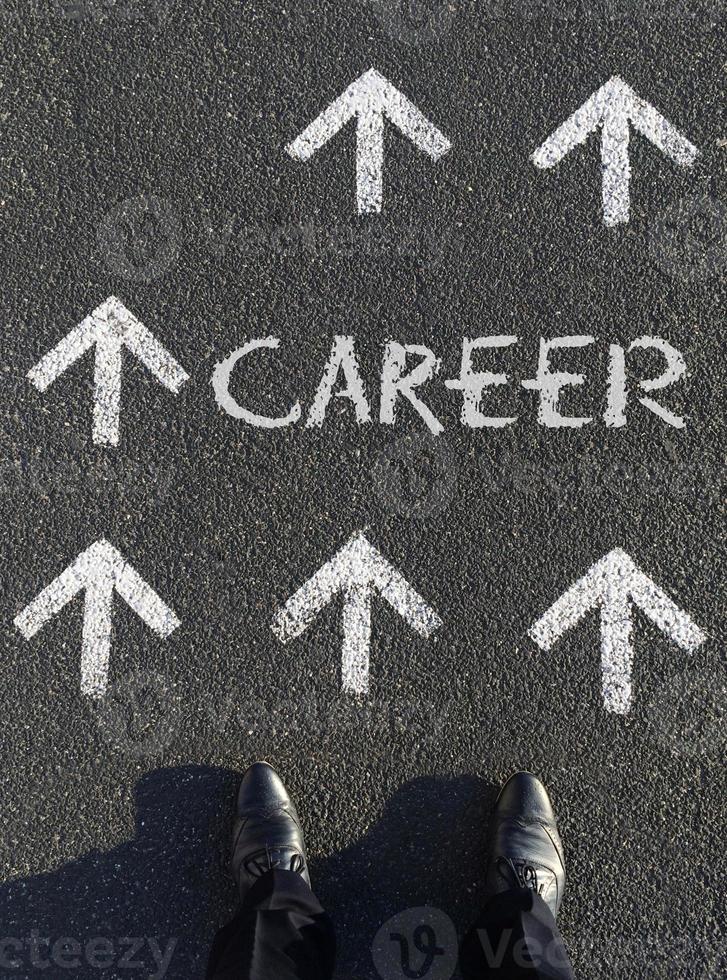 Moving forward - A man choosing his next career steps, looking down at multiple arrows and the word career written on the floor photo