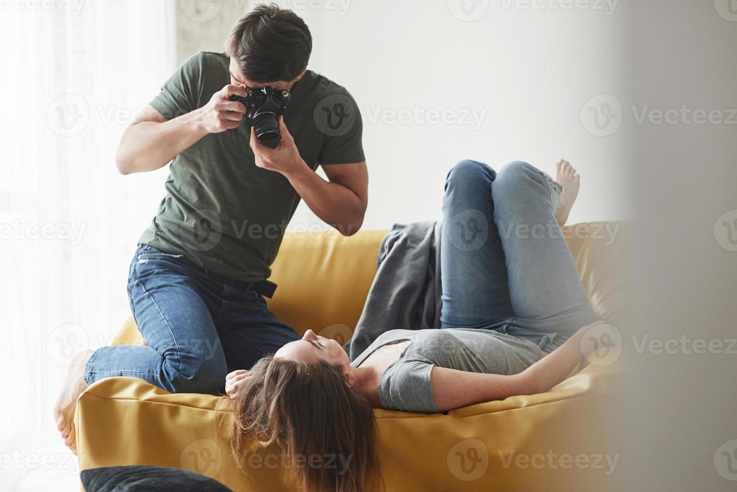 Nice shot. Photographer taking a shot of young girl that lying on the white sofa photo