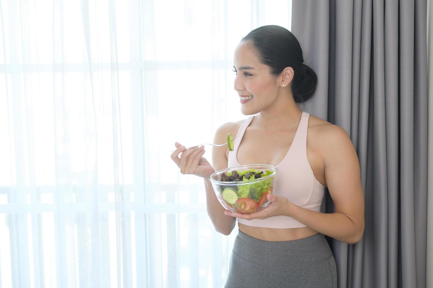 Fit young woman having salad after work out at home, sport and healthy lifestyle concept. photo