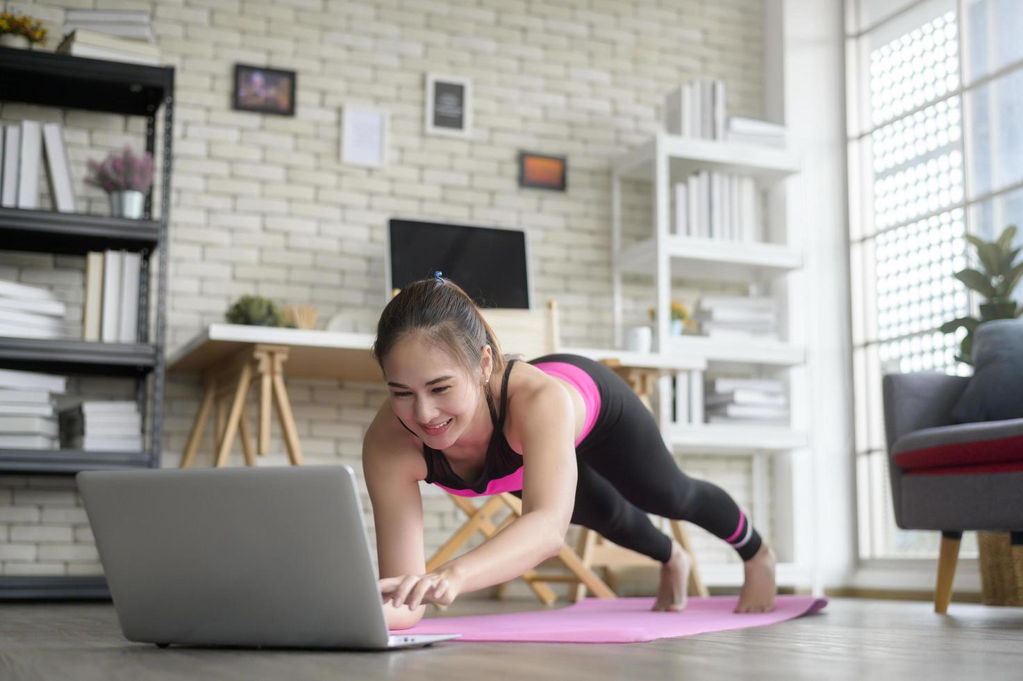 Fit young woman practicing yoga at home via online class with professional instructor, sport and healthy lifestyle concept. photo