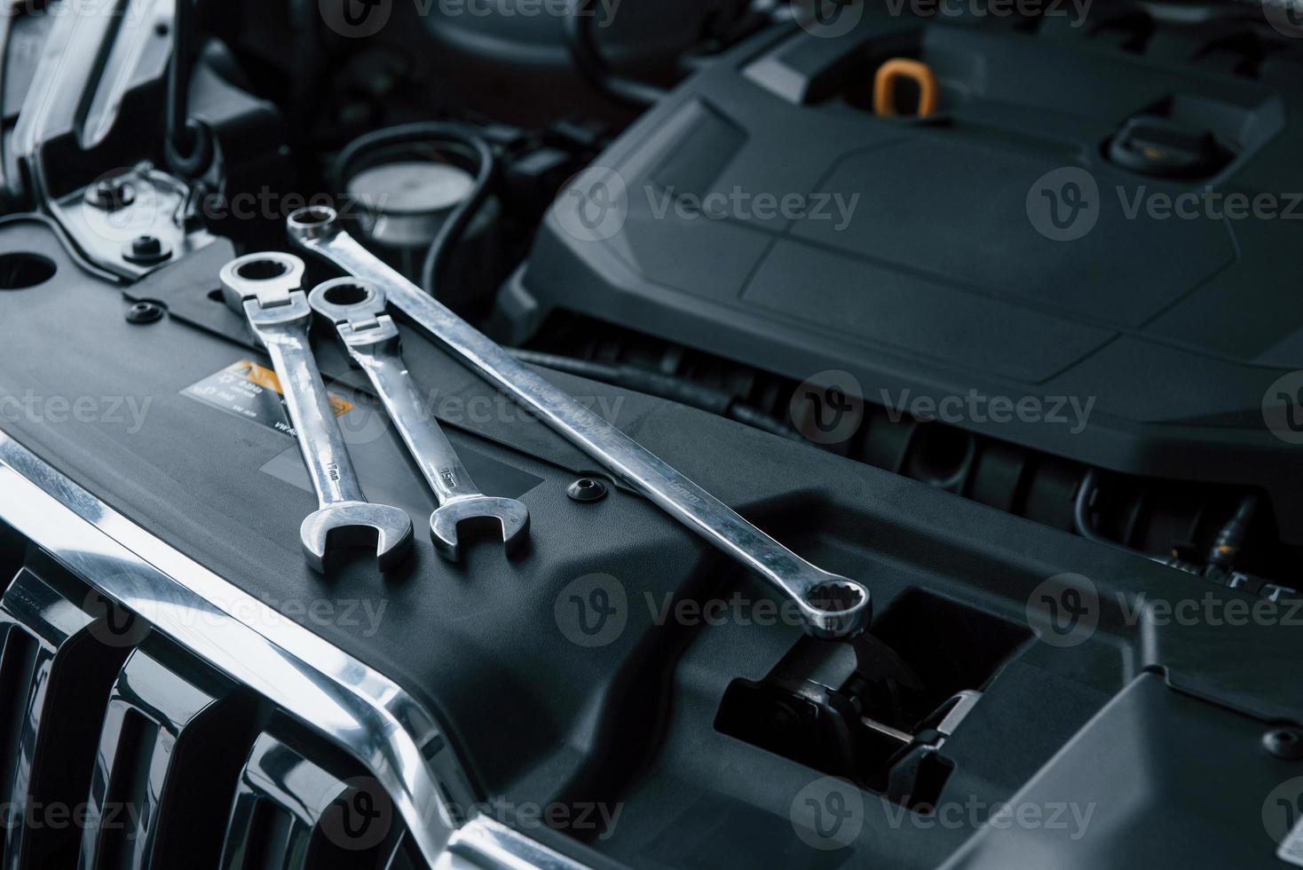 Black colored interior. Repair tools lying down on the engine of automobile under the hood photo