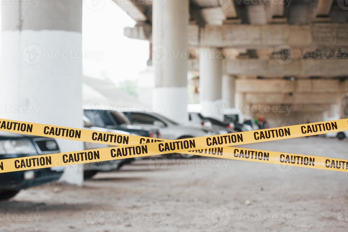 Forbidden territory. Yellow caution tape near the car parking lot at daytime. Crime scene photo