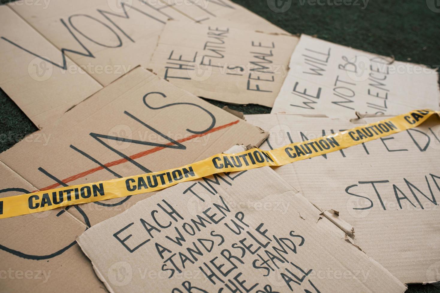 cinta de precaución en el papel. grupo de pancartas con diferentes citas feministas tiradas en el suelo foto