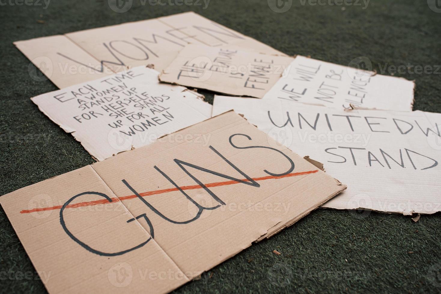 Say no to guns. Group of banners with different feminist quotes lying on the ground photo