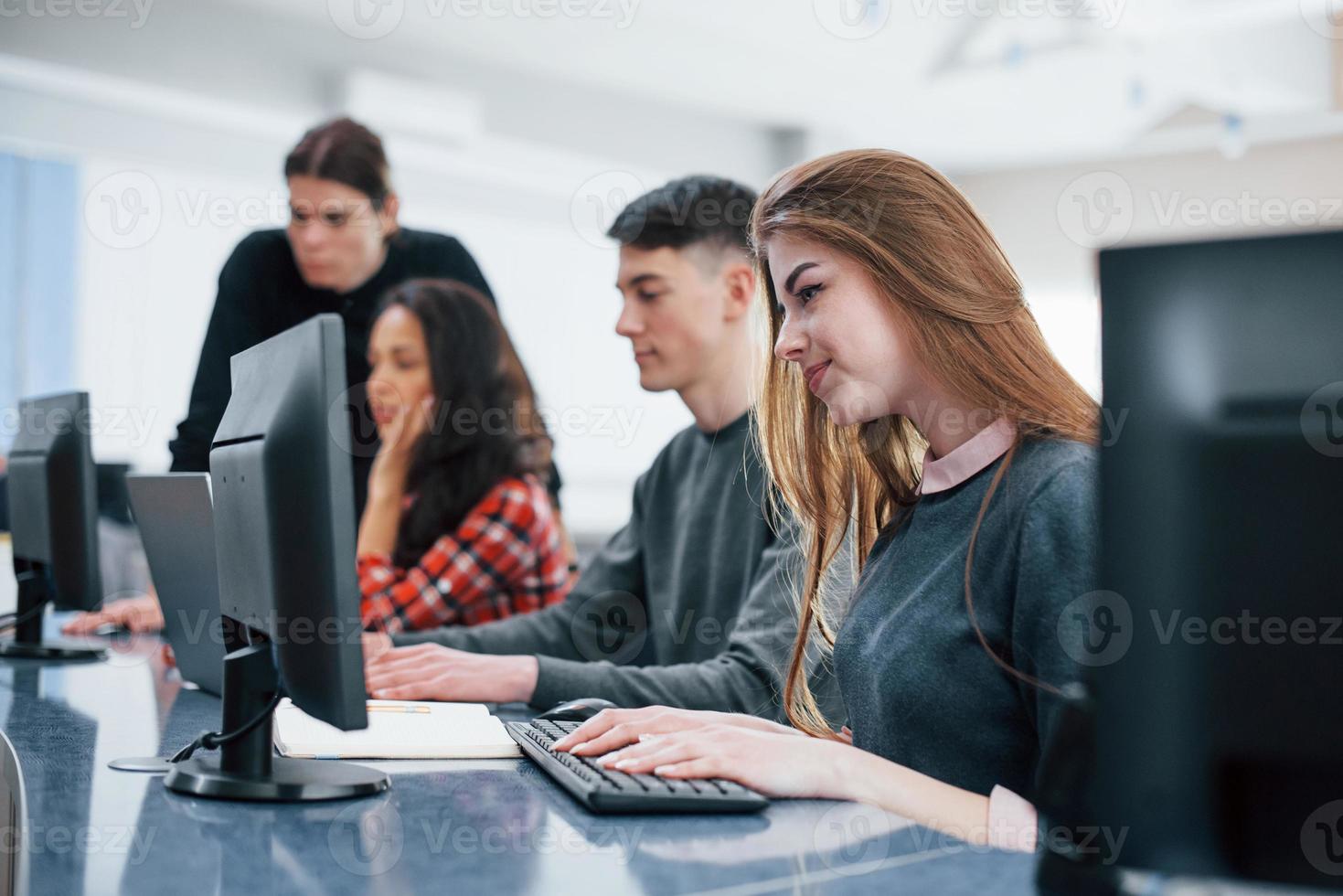 Computer screens. Group of young people in casual clothes working in the modern office photo