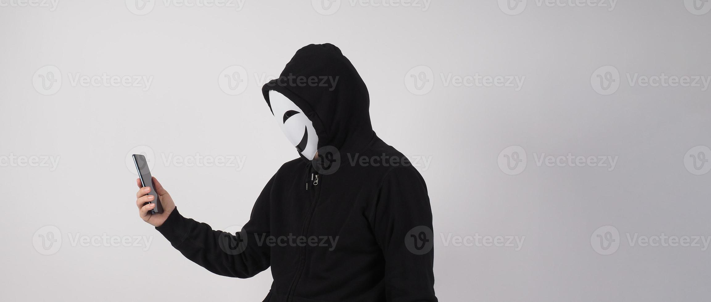 Anonymous hacker and face mask with smartphone in hand. photo