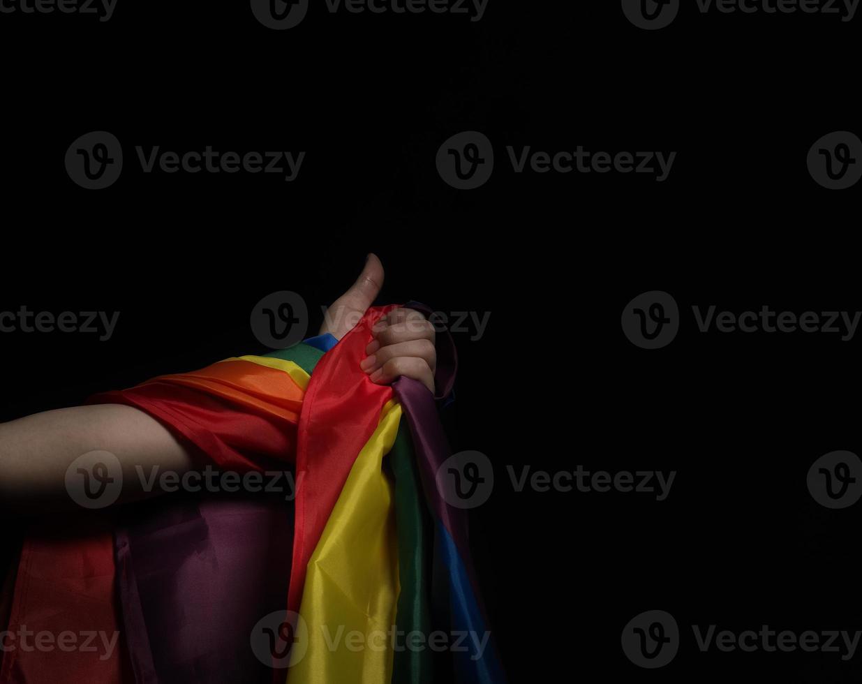 bandera del orgullo lgbtq sobre fondo negro. bandera del arco iris lgbt en mano gay. foto