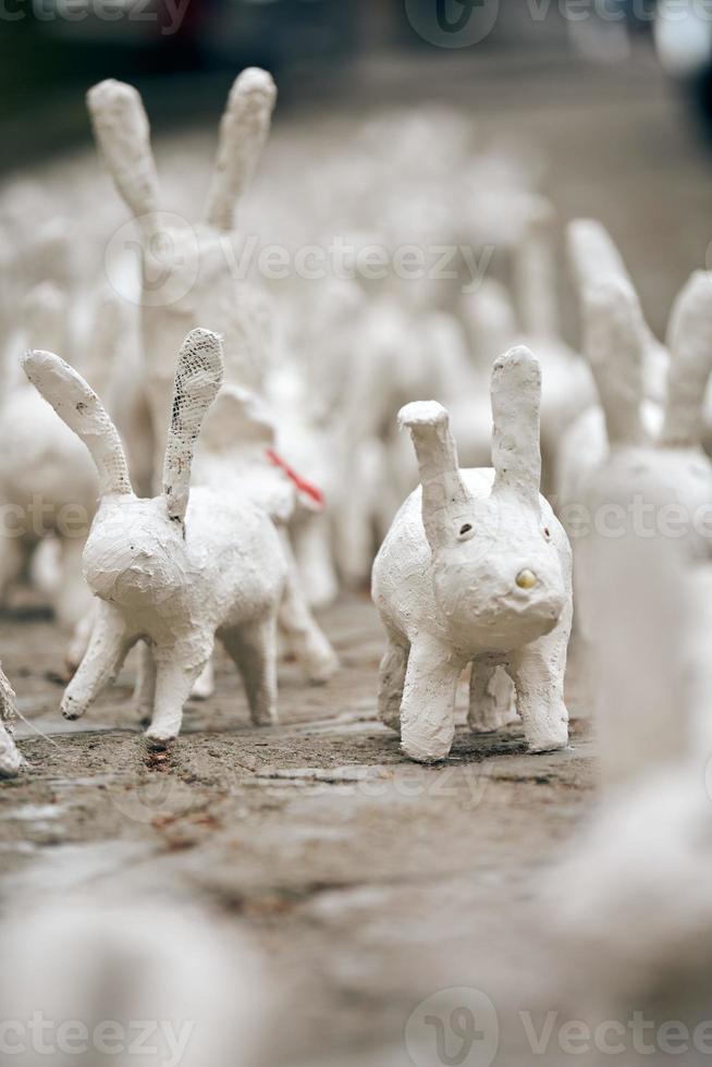 White rabbit statues made of plaster at outdoor art exhibition, funny white hares on street photo