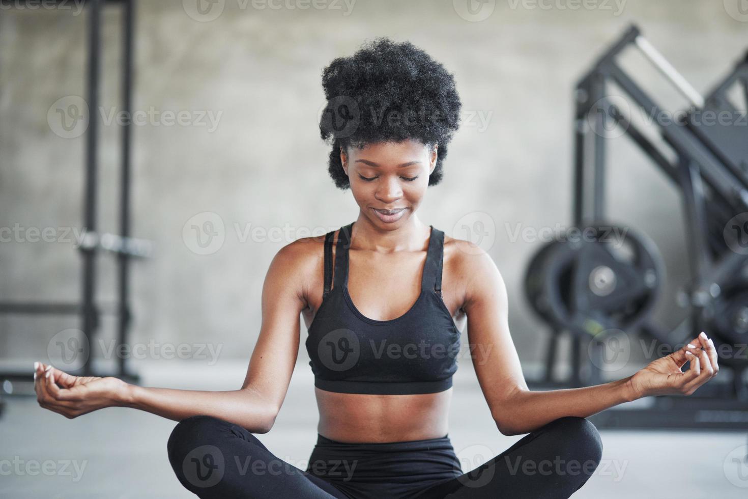 Calm mind. African american woman with curly hair and in sportive clothes have fitness day in the gym photo