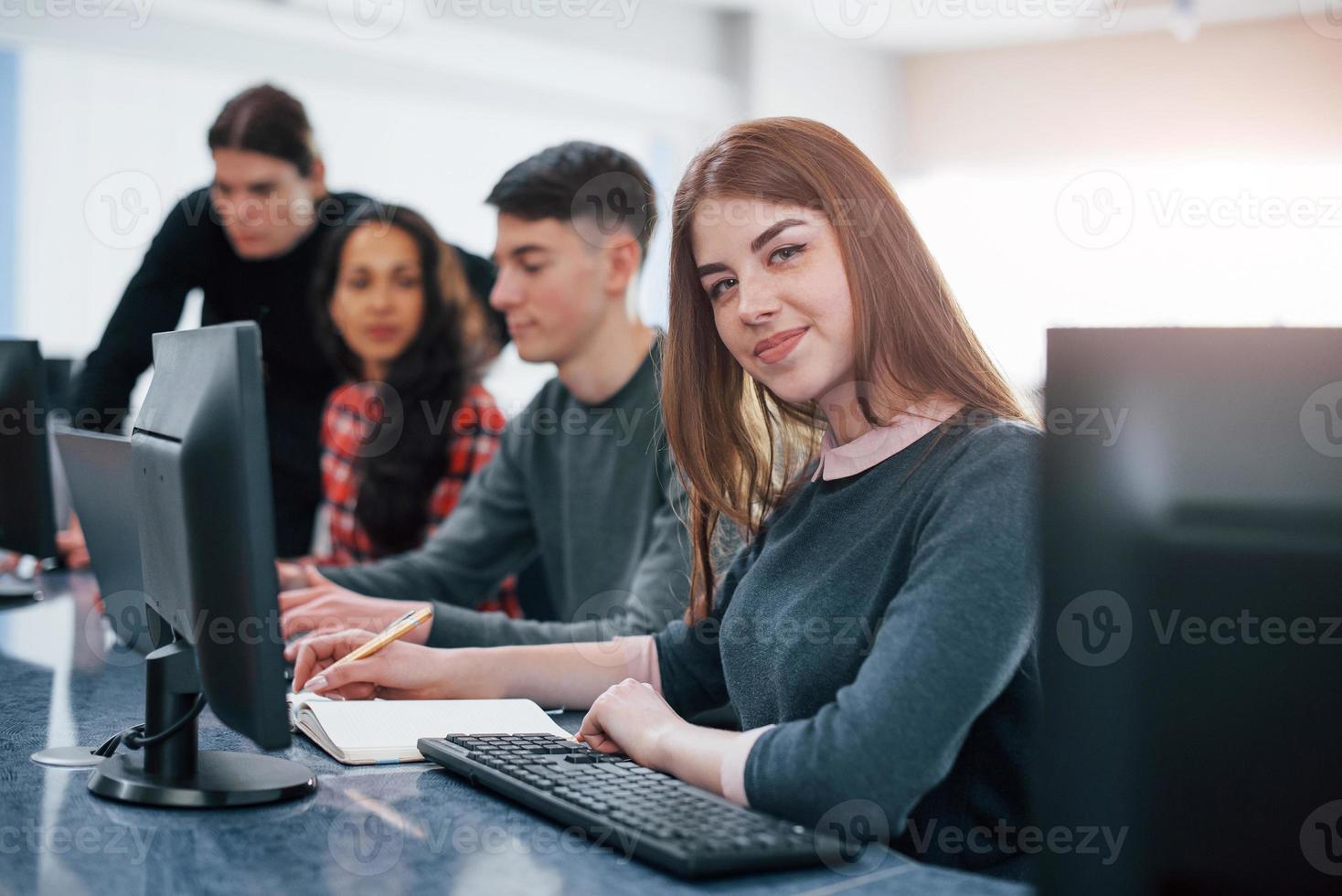Pretty girl. Group of young people in casual clothes working in the modern office photo