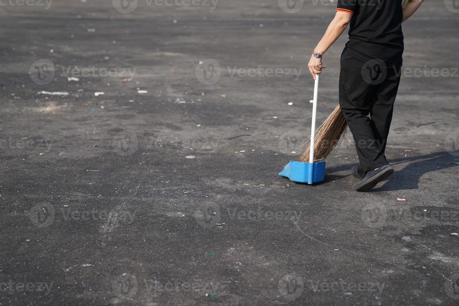 cleaner sweep trash in large asphalt outdoor area at noon. photo