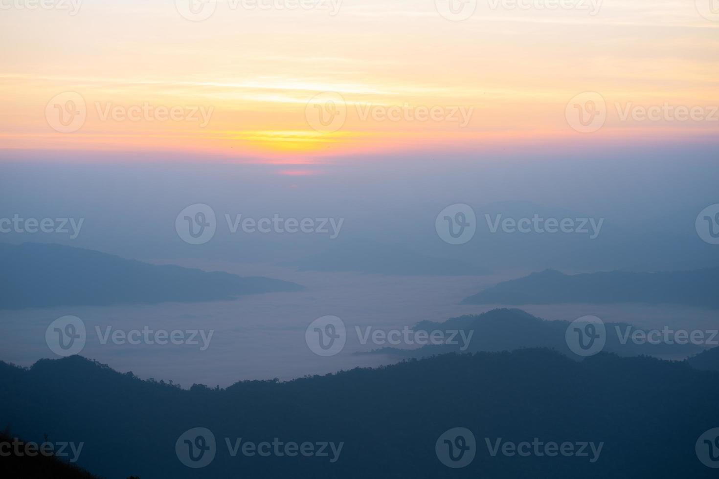 The sunrise at the mountain with the fog and cloud cover it. photo