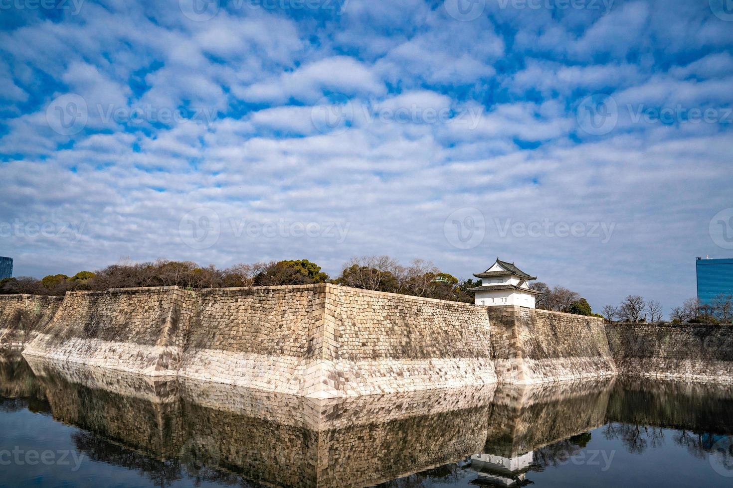 Osaka Castle stone wall with water reflect below. photo