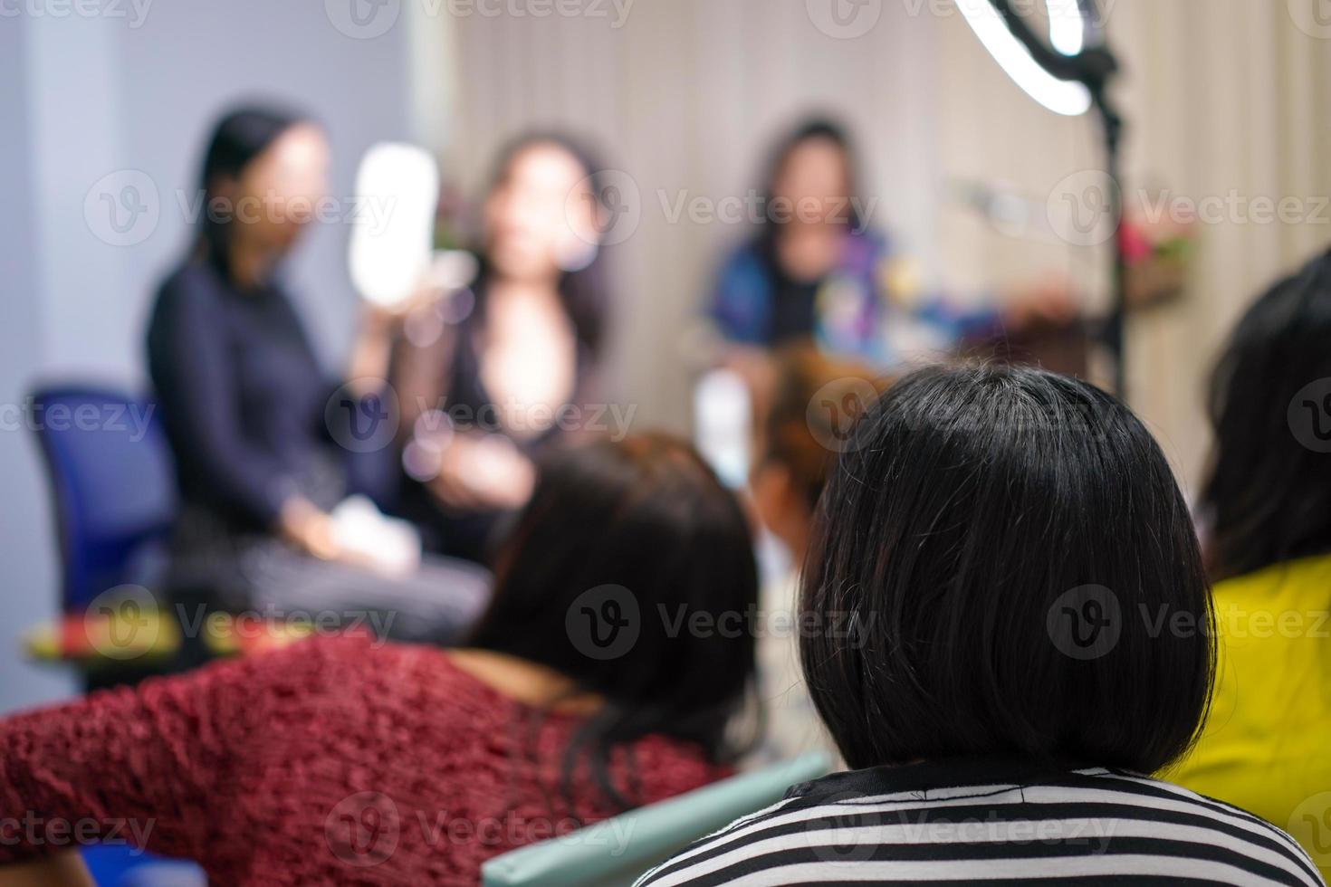 audience and participant listen to teacher and lecturer at the front of stage about women face make up. photo