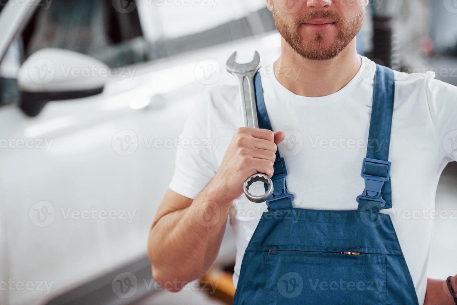 Unshaved man. Employee in the blue colored uniform works in the automobile salon photo