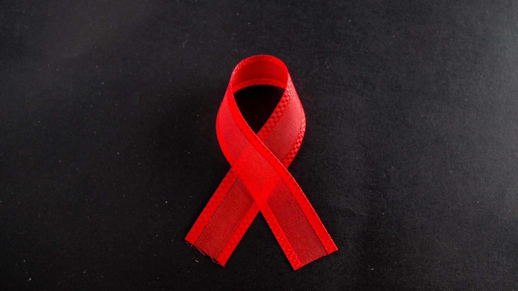 cinta roja de la campaña de prevención del sida, cáncer de riñón, cáncer de cabeza y cuello, hepatitis. cinta aislada sobre fondo negro. Concientización sobre la donación de sangre. foto