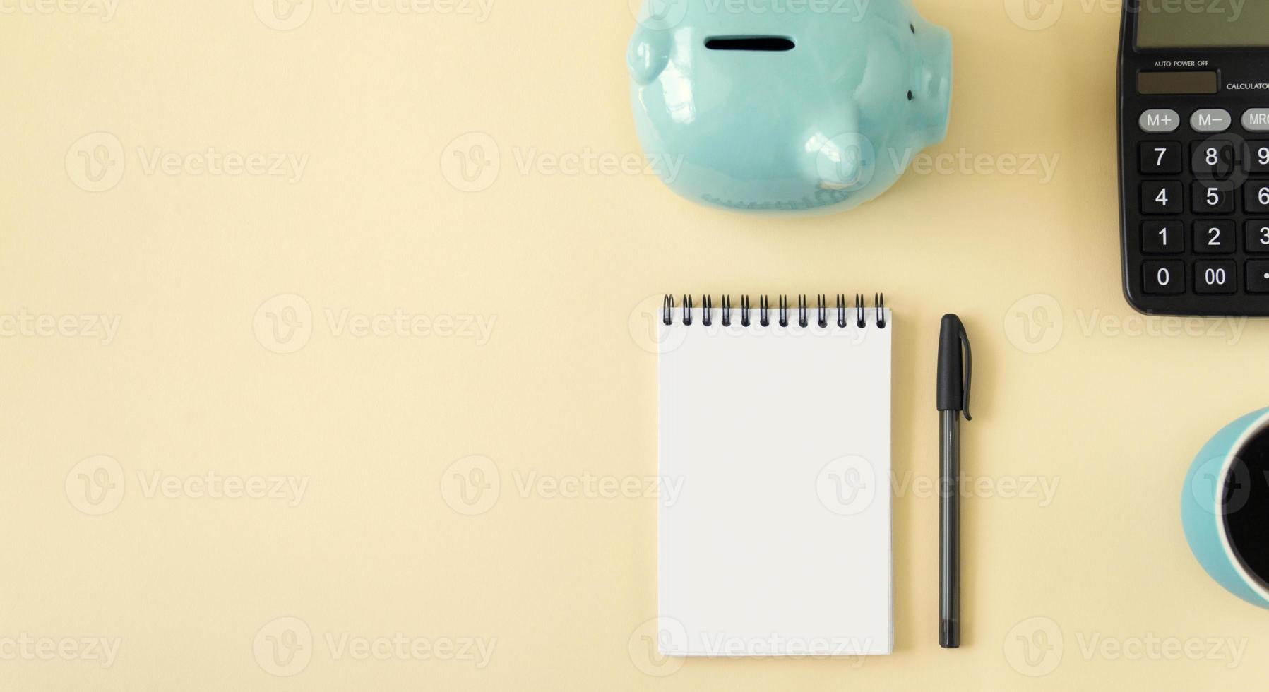Planning concept with notepad, piggy bank, calculator and coffee. Banner of yellow pastel color with copy space. photo
