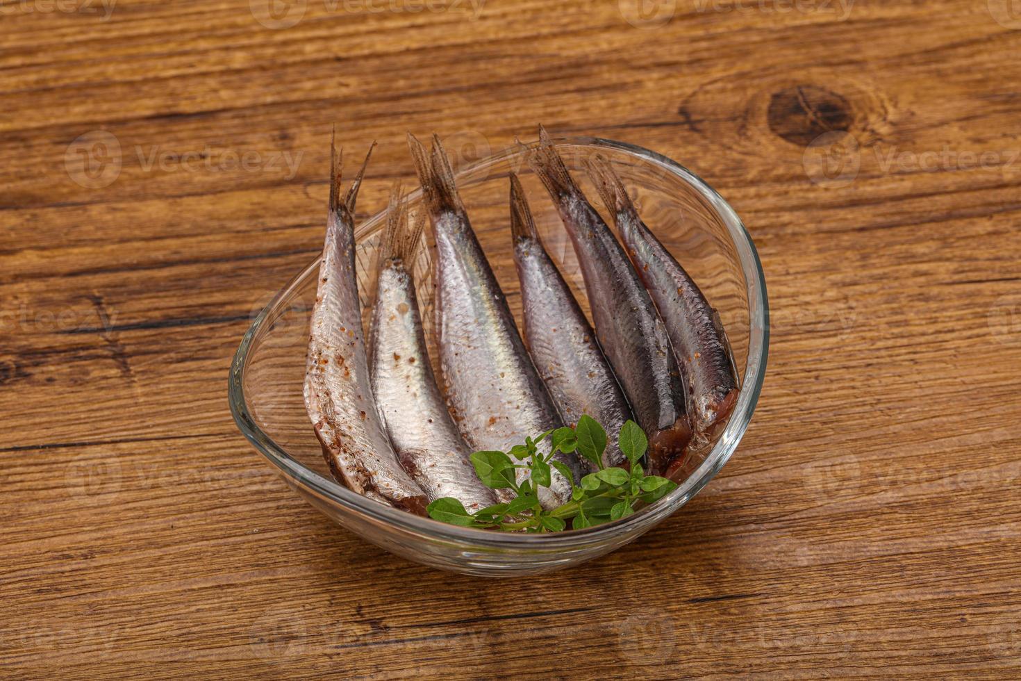 Anchovies in the bowl served basil leaves photo