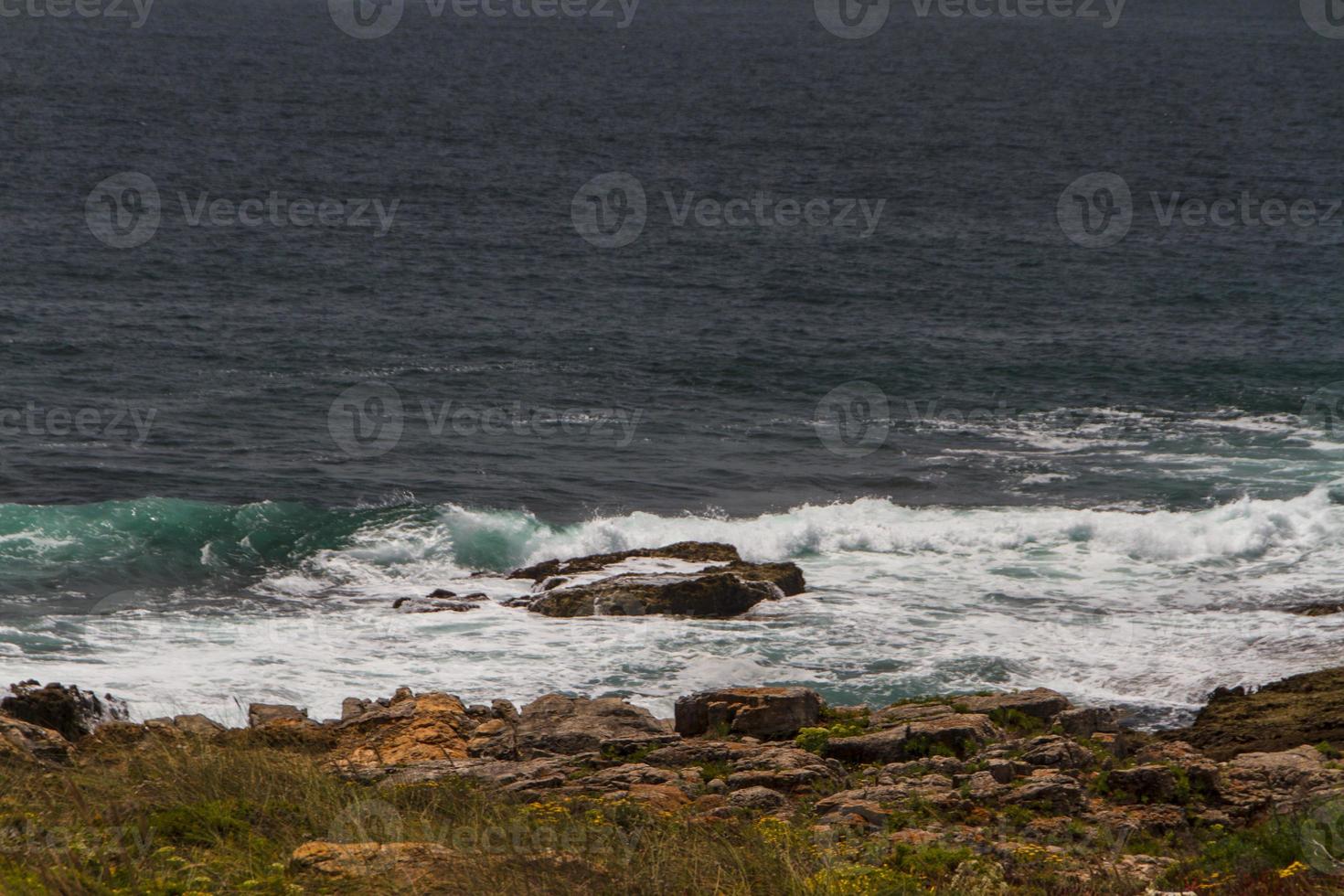 The waves fighting about deserted rocky coast of Atlantic ocean, Portugal photo