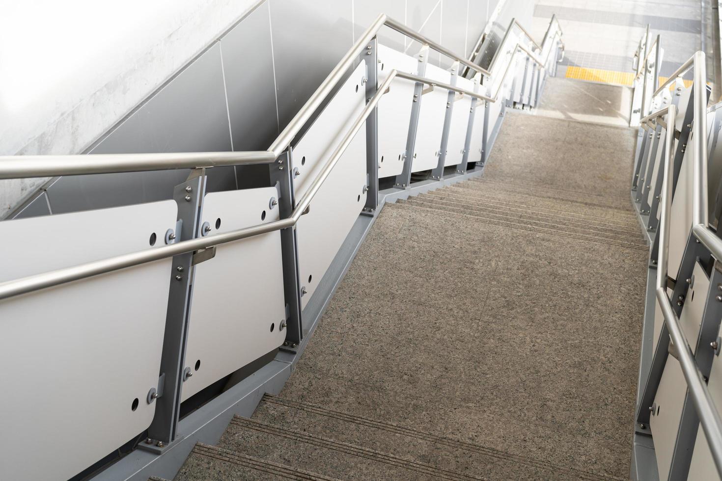 escalera pública en la estación o centro comercial para salida, entrada. escalera dentro del metro subterráneo con pasamanos de acero limpio. una escalera vacía en una estación de metro foto