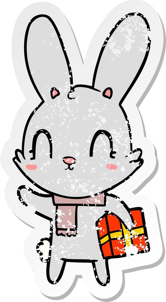 distressed sticker of a cute cartoon rabbit with christmas present vector