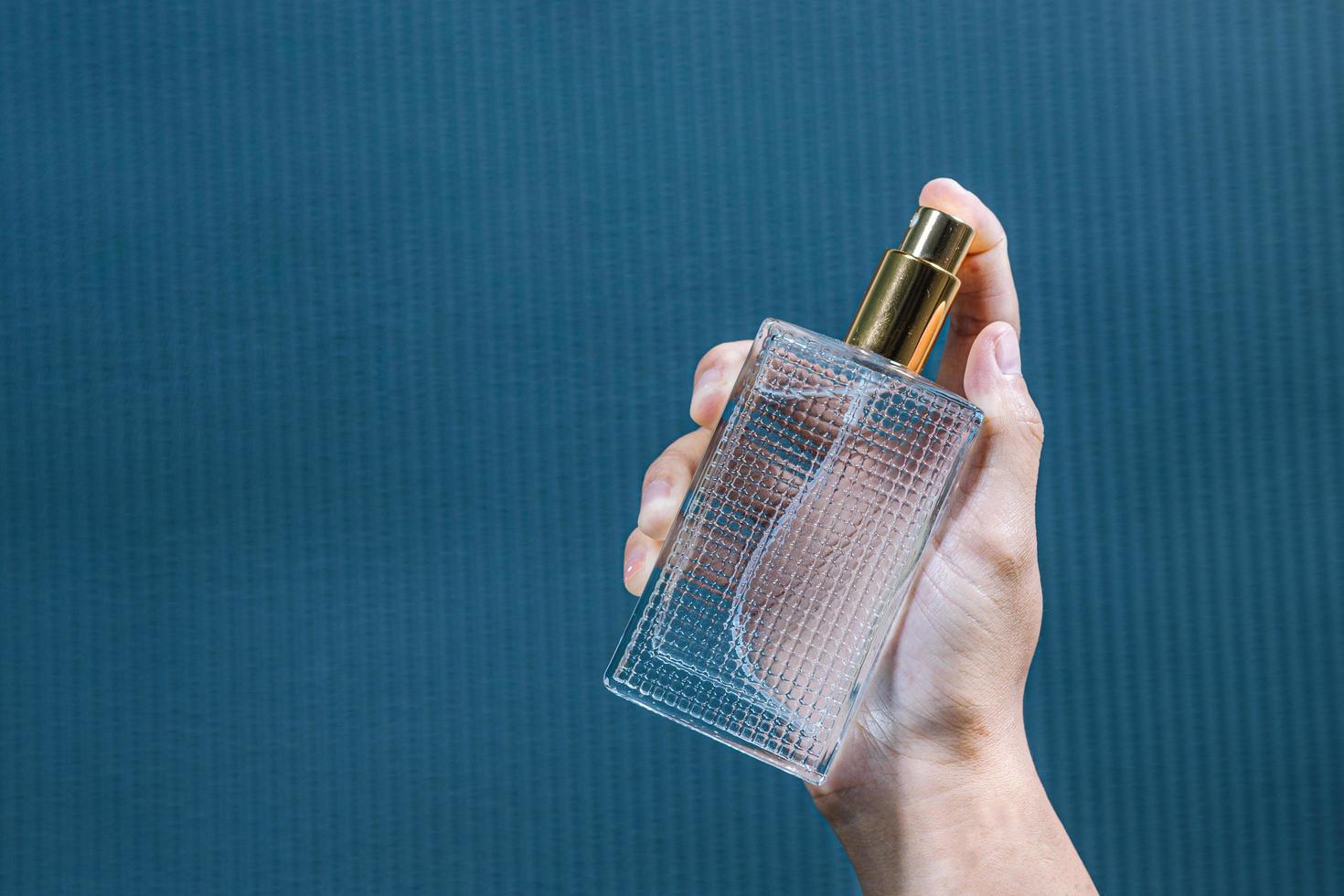 Young Woman spraying perfume on blue background, closeup photo