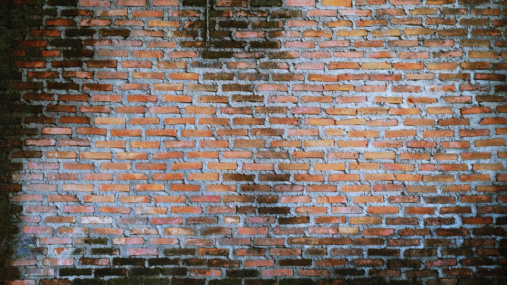 la pared de ladrillo antiguo tiene manchas marrones y arañazos. la arquitectura abandonada es una cosa terrible. foto