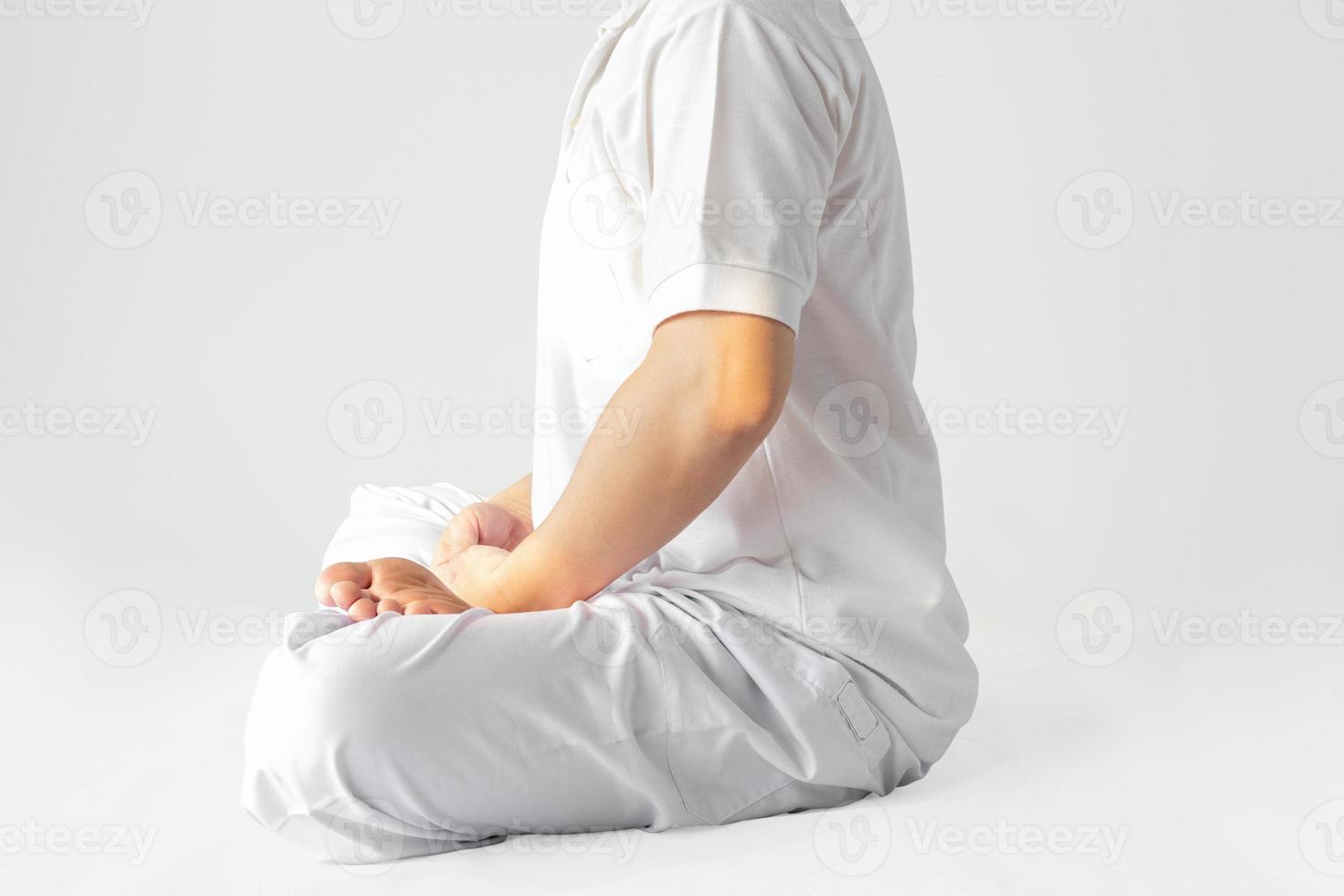 un hombre con una túnica blanca meditando sobre un fondo blanco con un sendero recortado. foto