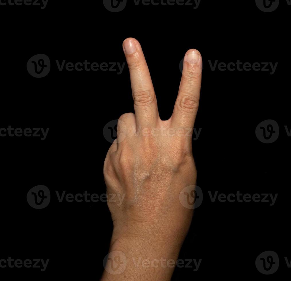 The man's hand that holds two fingers is a V sign, meaning victory. Or still means peace and contempt for challenges on black background photo