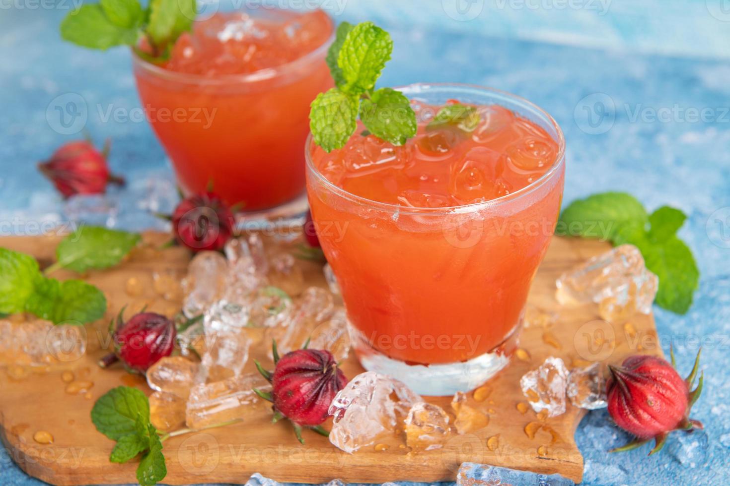 Iced roselle tea glass with fresh roselle fruit on wooden table for healthy herbal drink concept. herbal organic tea for good healthy. photo