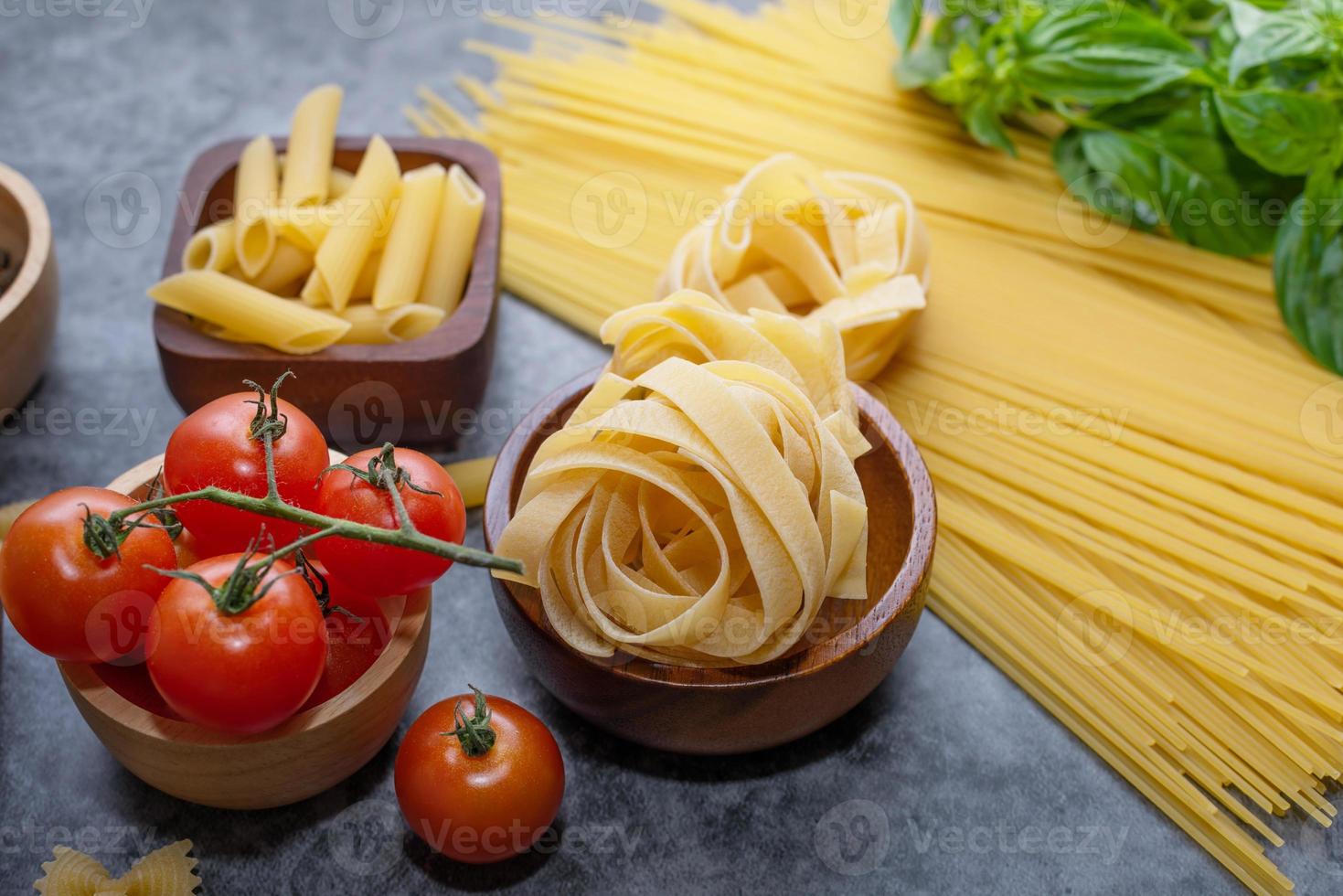 Mixed dried pasta selection on wooden background. composition of healthy food ingredients isolated on black stone background, top view, Flat lay photo