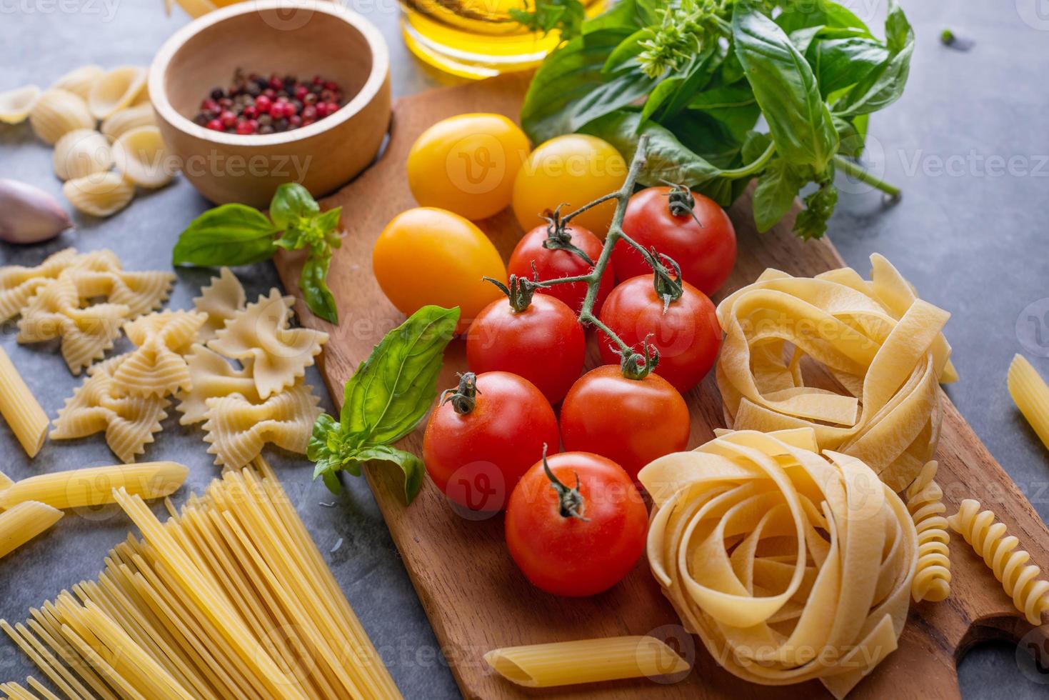 Mixed dried pasta selection on wooden background. composition of healthy food ingredients isolated on black stone background, top view, Flat lay photo