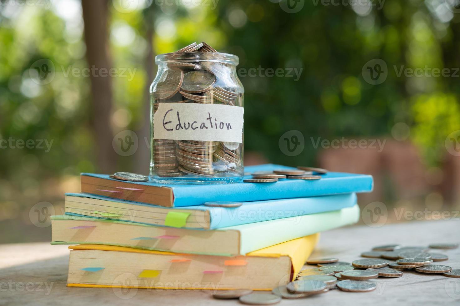 putting money coins saving in glass bottle for concept investment mutual fund finance and business, placed on the textbook. content money saving for education. photo