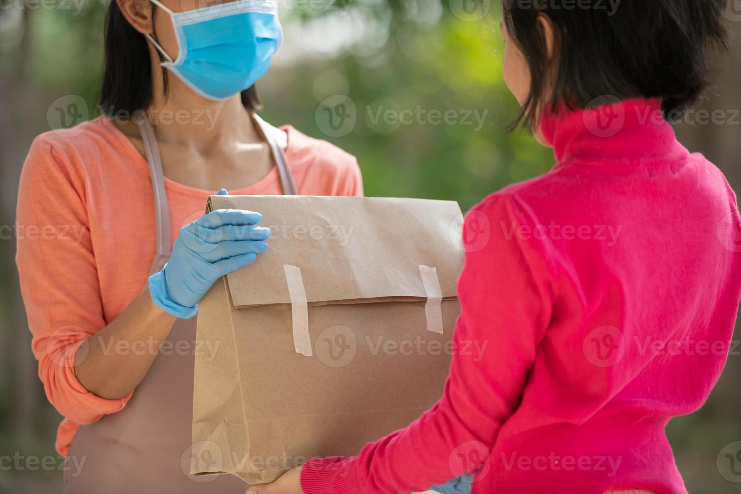 postman, delivery man wearing mask carry small box deliver to customer in front of door at home. woman wearing mask prevent covid 19, coronavirus infection outbreak. home delivery shopping concept. photo