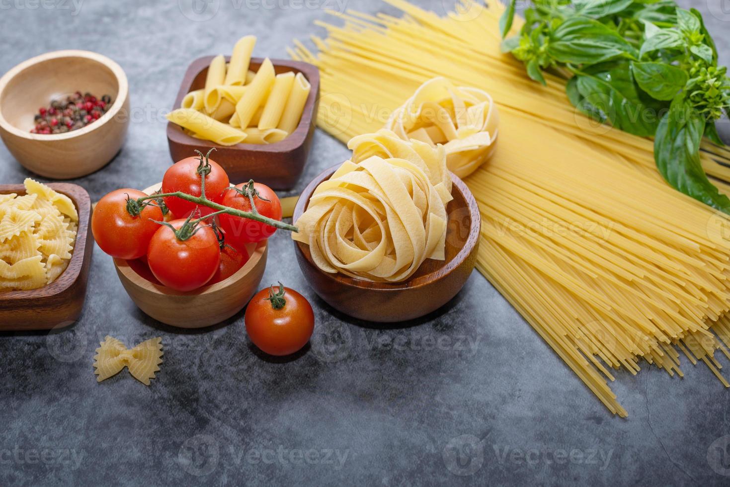 Mixed dried pasta selection on wooden background. composition of healthy food ingredients isolated on black stone background, top view, Flat lay photo