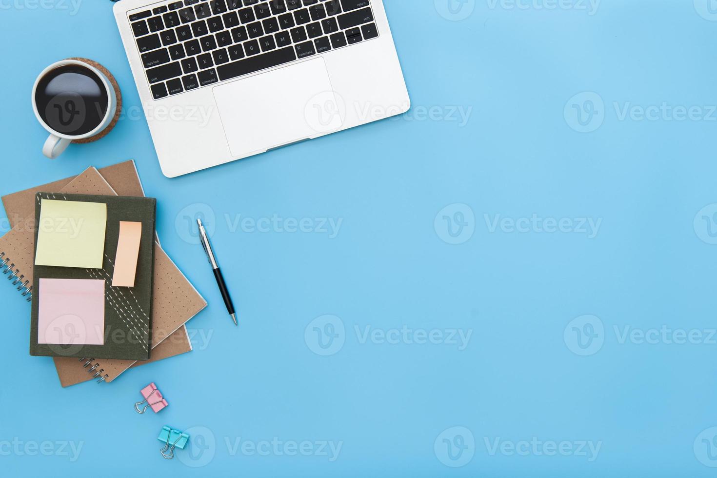Modern workspace with coffee cup, laptop, pen, paper, notebook, tablet and laptop copy space on blue color background. top view. flat lay style. photo