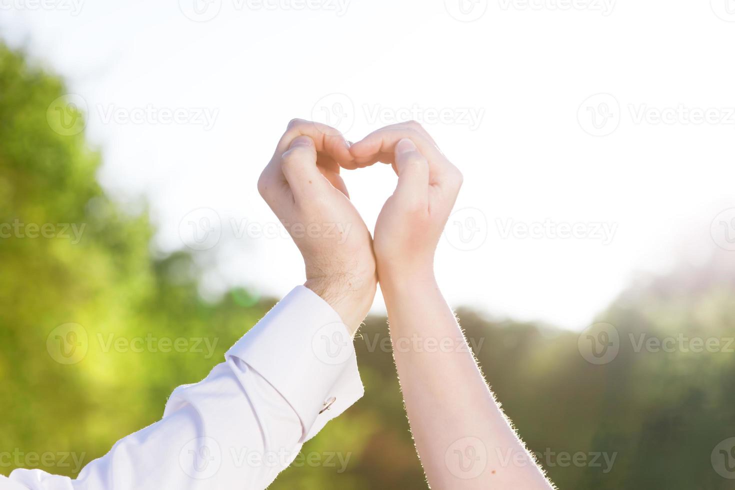 Couple in love making a heart shape with their hands outdoors. photo