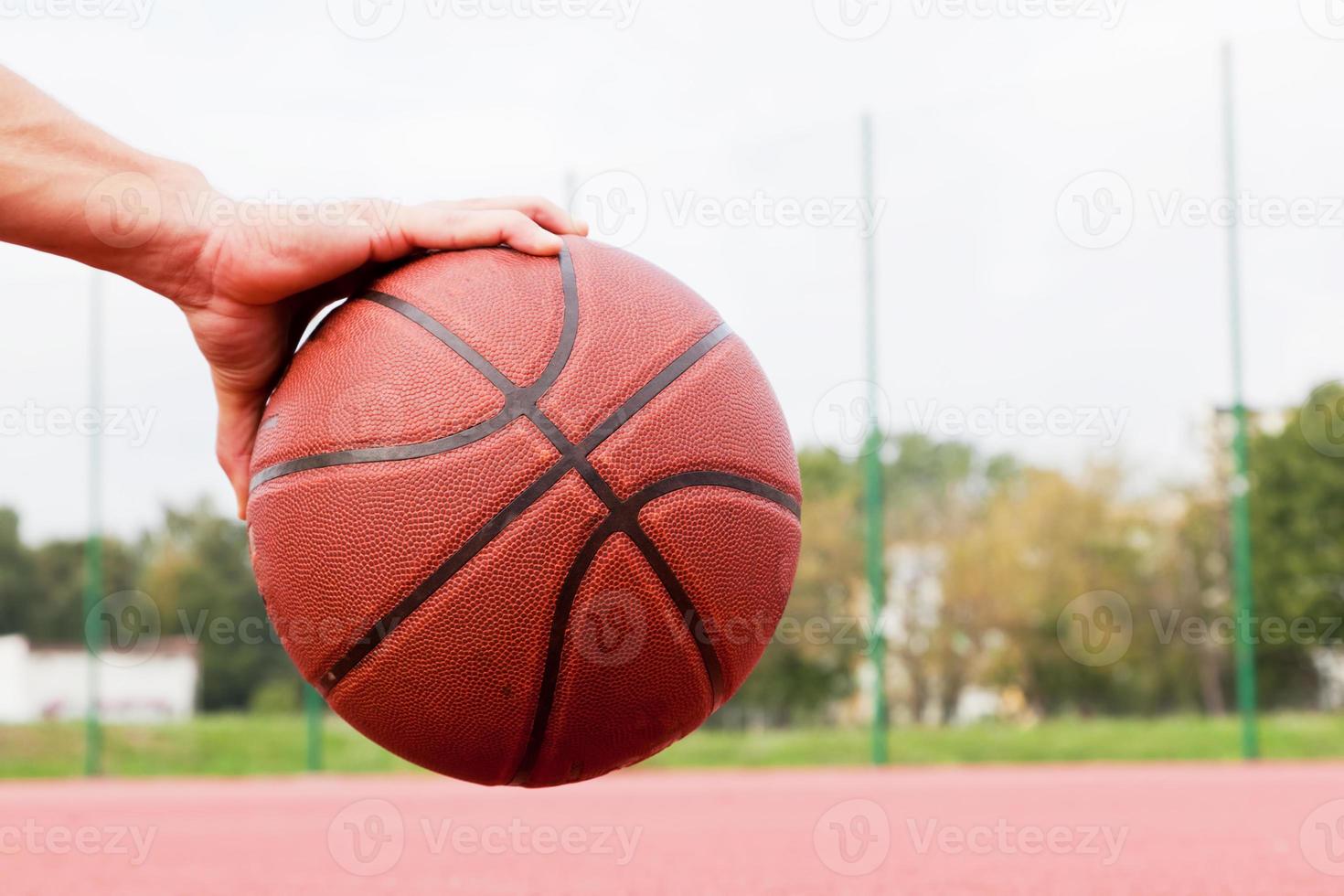 Young man on basketball court. Sitting and dribbling with ball photo