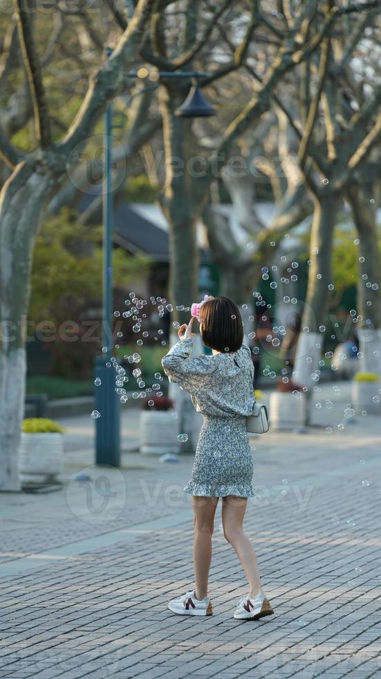 One well dressed girl play with the blowing bubbles in the park photo