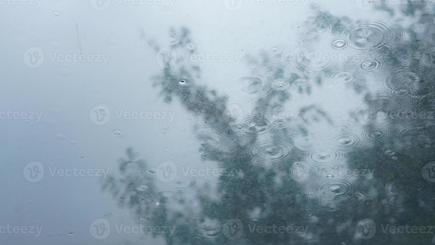 The glass window covered by the rain droplets and waterfall in the rainy day photo