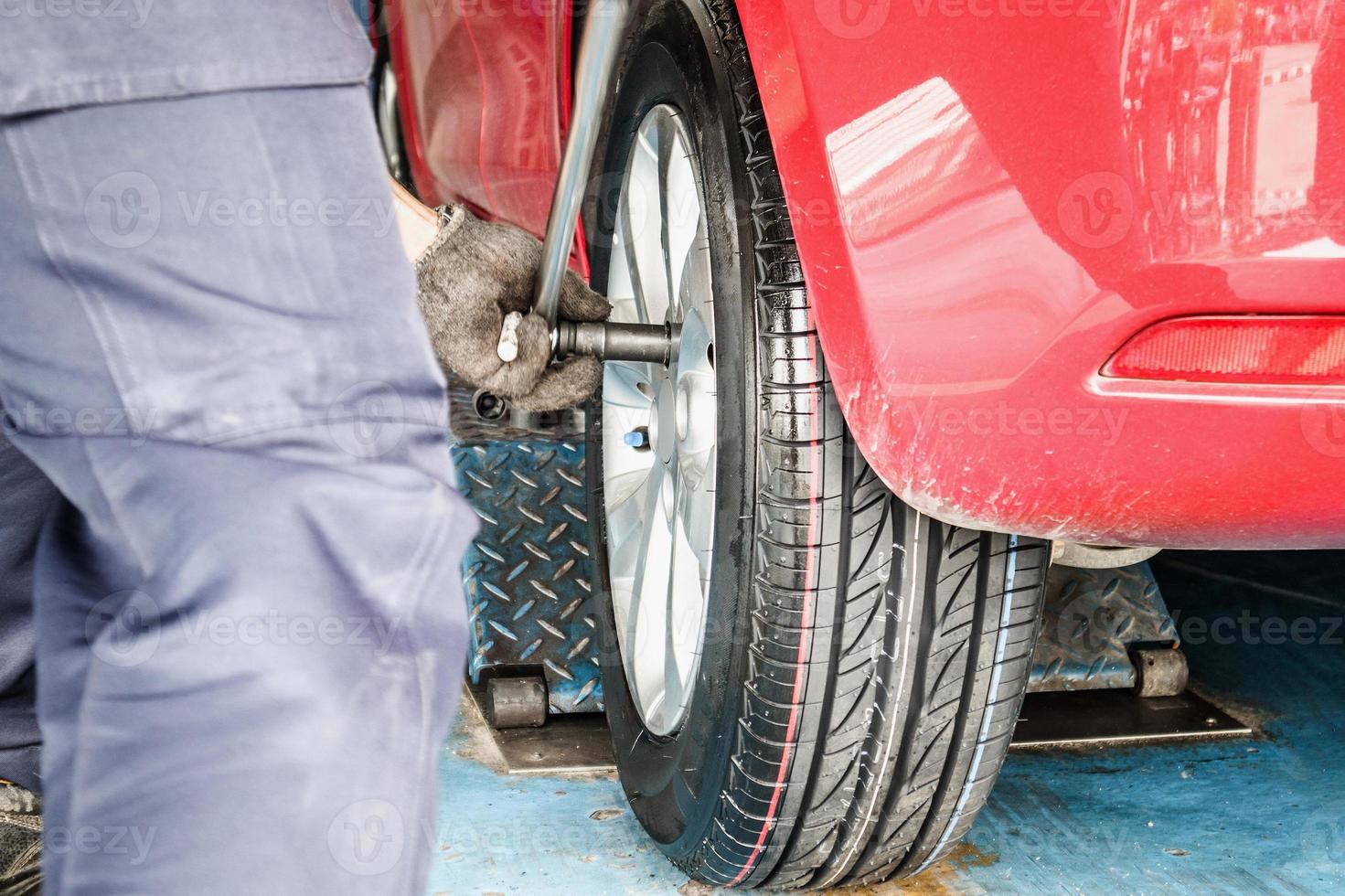 Tire replacement service, Mechanic with wrench working at auto repair shop changing car wheel photo